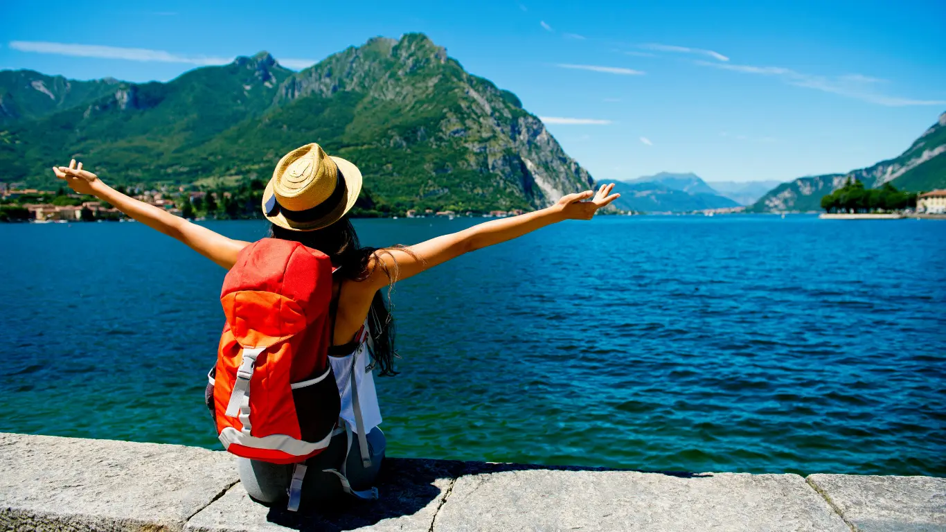 Ragazza in viaggio con zaino rosso di fronte al mare