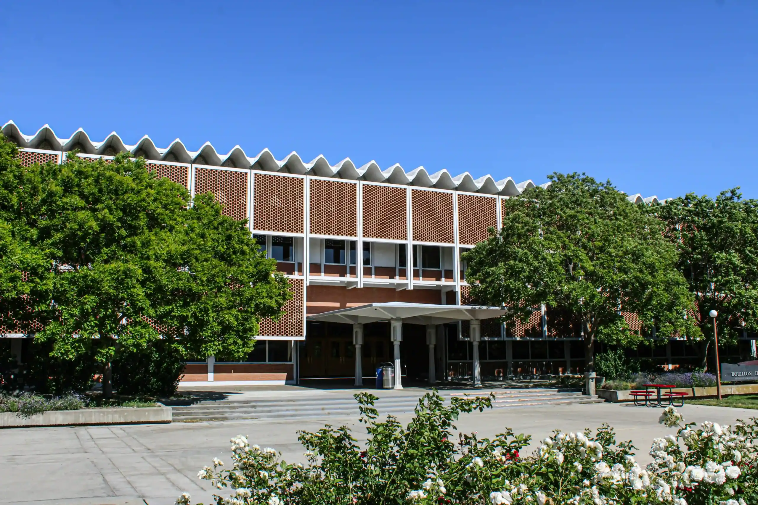 Edificio scolastico con alberi e fiori.