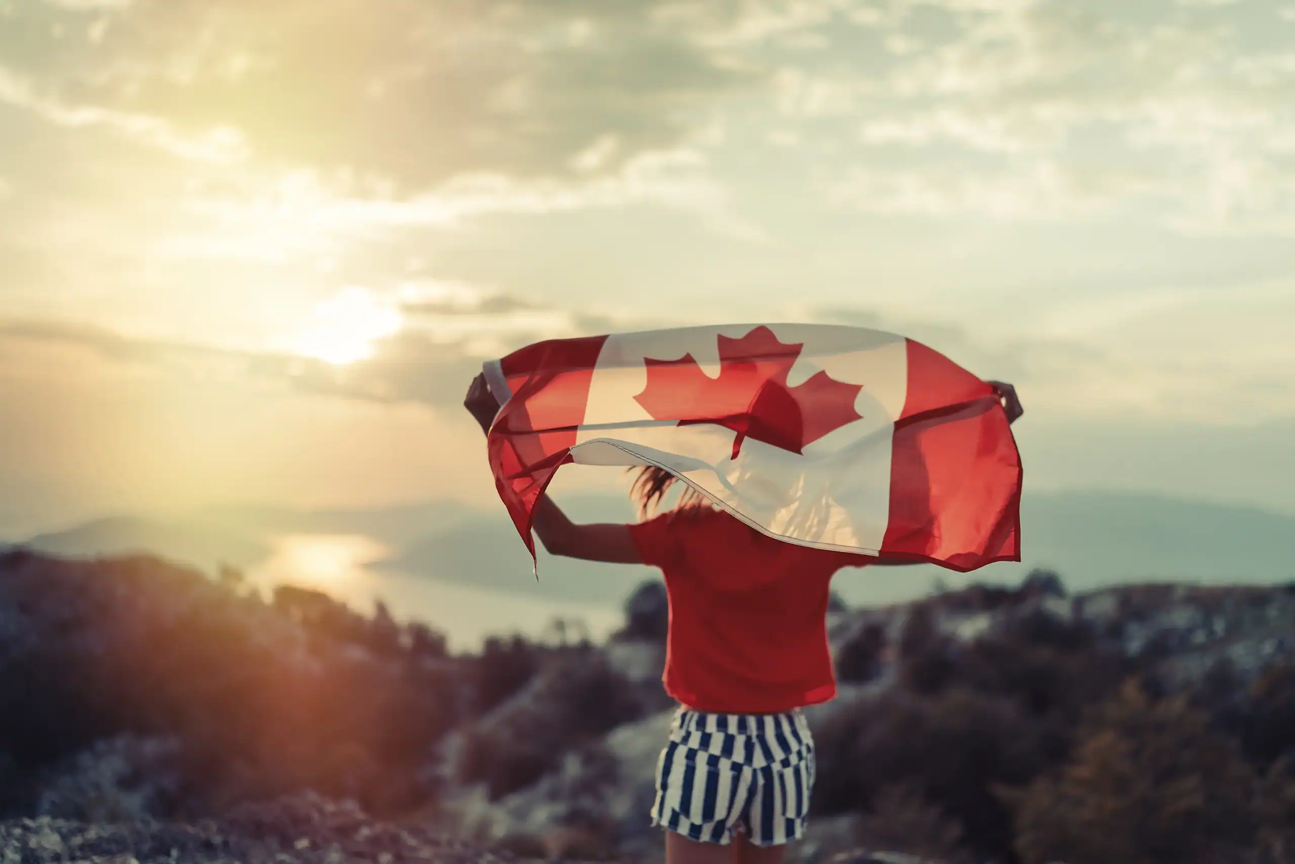 Ragazza con bandiera canadese al tramonto