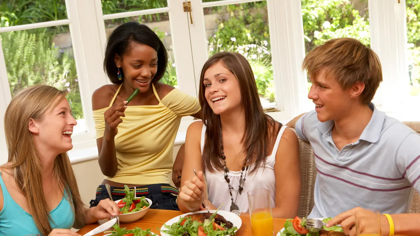 Teenagers che cenano seduti a tavola